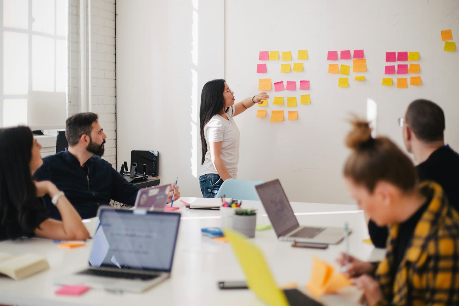 A team planning work together at a whiteboard covered in sticky notes